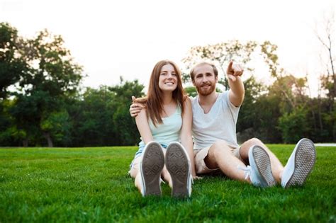 Free Photo Young Beautiful Couple Smiling Sitting On Grass In Park