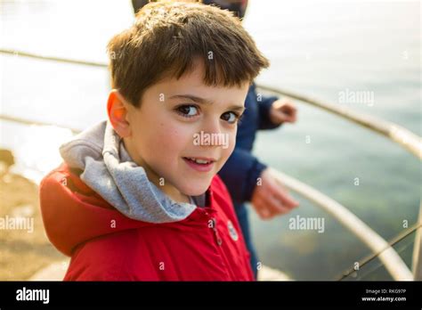 Portrait Of 9 Year Old Boy With Red Jacket Outside As A Lake