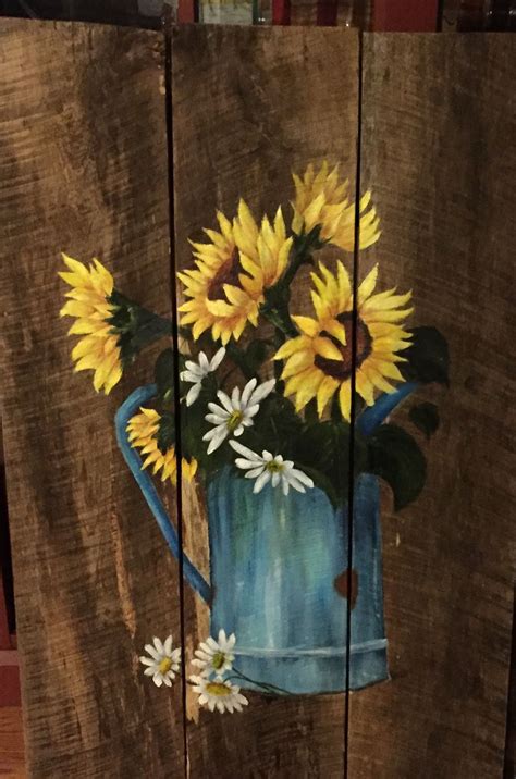A Painting Of Sunflowers In A Blue Watering Can Painted On Wood Planks
