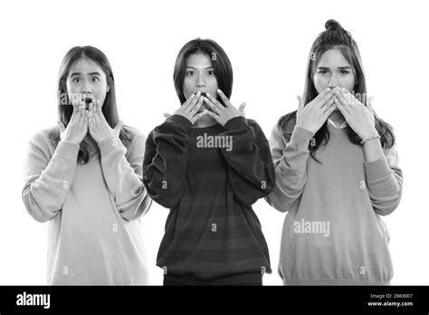 Studio Shot Of Three Young Asian Woman Friends Covering Mouth While