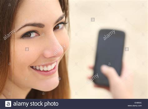 Close Up Portrait Of A Smiley Woman Using A Smart Phone On The Beach