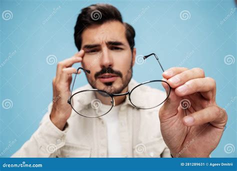 Close Up Portrait Of A Brunette Man Looking Through Glasses That He Holds In His Hands Eye