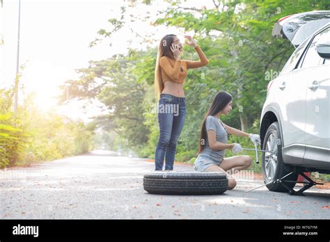 Female Driver Changing Tyre On Her Broken Car And Her Friend Is Calling For Help Stock Photo Alamy