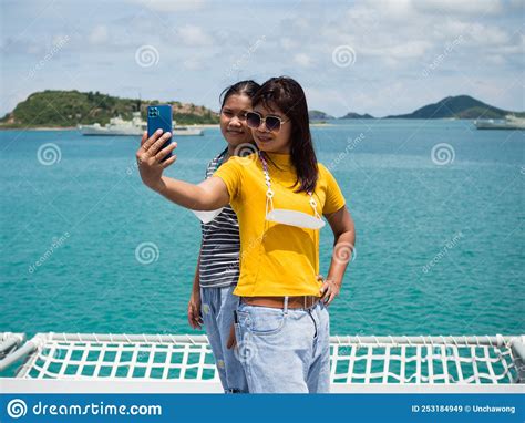 A Woman In A Yellow Shirt Is Holding A Phone To Take A Selfie With A Girl In A Gray Shirt With