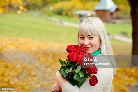 Pirang Paruh Baya Yang Lucu Berpose Dengan Buket Mawar Merah Di Taman
