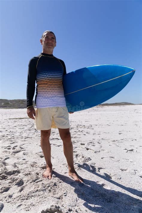 Senior Caucasian Man Holding A Surfboard At The Beach Stock Photo
