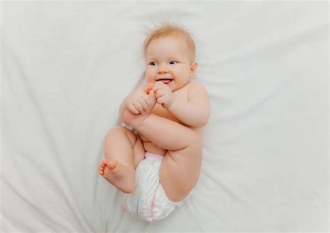 Premium Photo A Happy Baby In Diapers Is Lying On A White Bed And