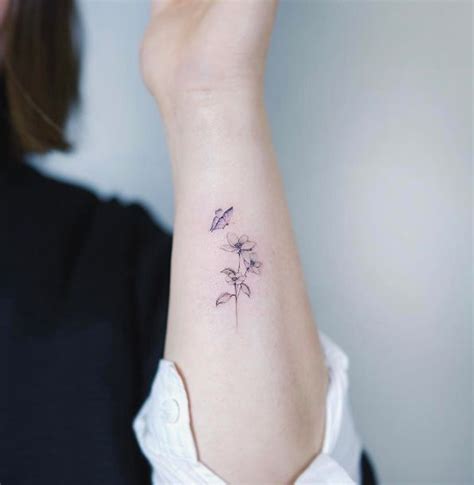 A Womans Arm With A Small Flower Tattoo On The Left Side Of Her Wrist