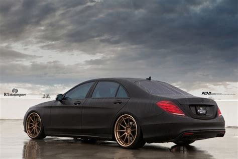A Black Car With Gold Rims Parked In Front Of A Cloudy Sky