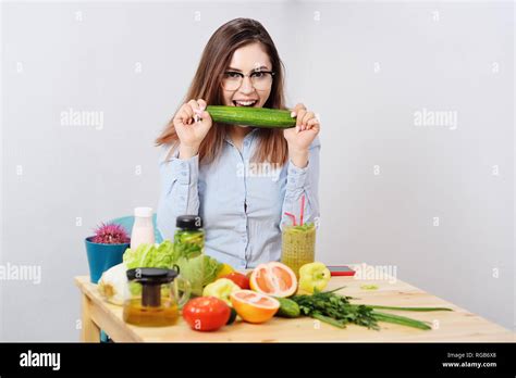 Beautiful Young Girl Biting A Big Cucumber On The Table Background With