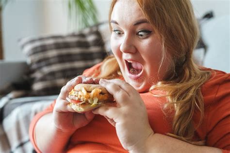 mulher carnudo que senta em casa o hamburguer pronto para comer excitado imagem de stock