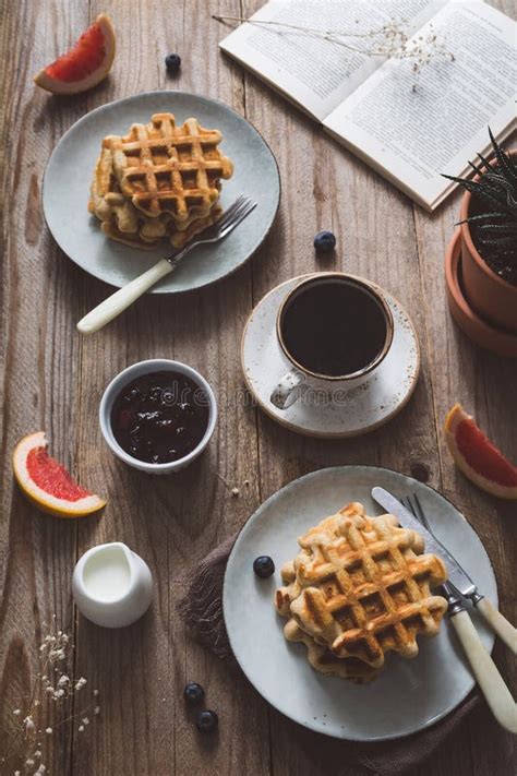 Breakfast Table With Waffles Coffee Jam Fruits And Book For Reading