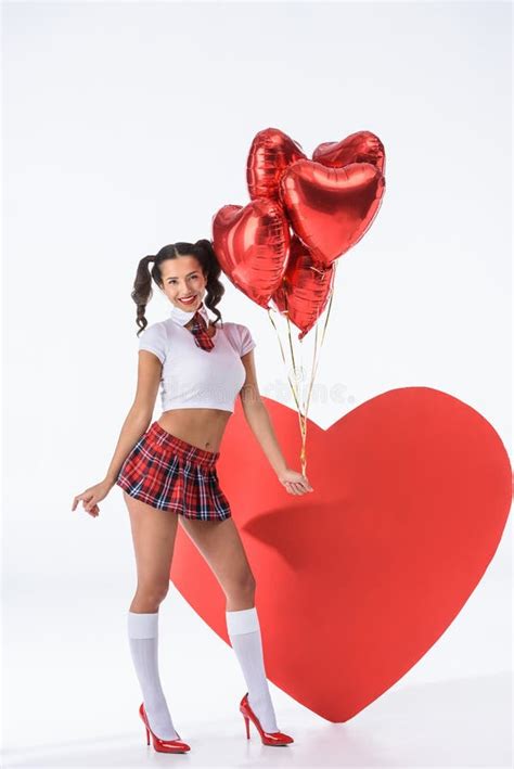 Young Schoolgirl With Helium Balloons In Shape Of Hearts In Front Of