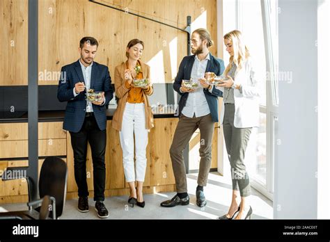 Group Of A Young Office Workers Eating Salads And Drinking Coffee At