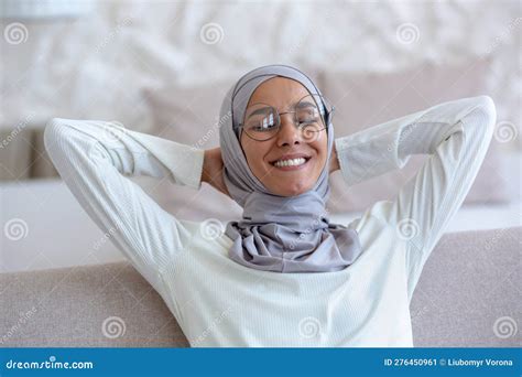 Arab Young Female Student In Hijab And Glasses Sitting On Sofa At Home