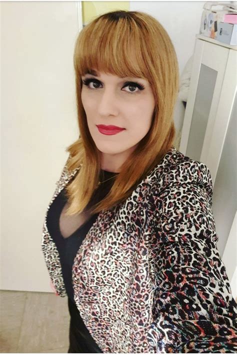 a woman with red hair and leopard print jacket posing in front of a white refrigerator