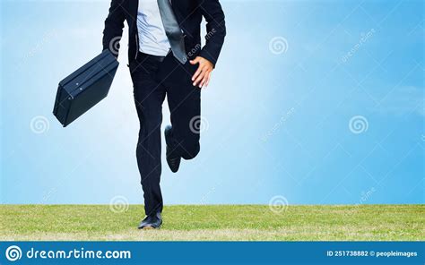 Male Business Executive Running With A Briefcase On A Field Cropped