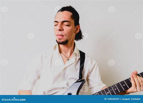 Young Millenial Man Sitting On The Floor Of Home Playing An Electric