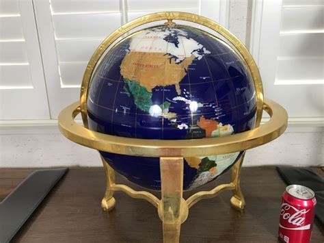 A Blue And Gold Globe Sitting On Top Of A Wooden Table Next To A Can Of