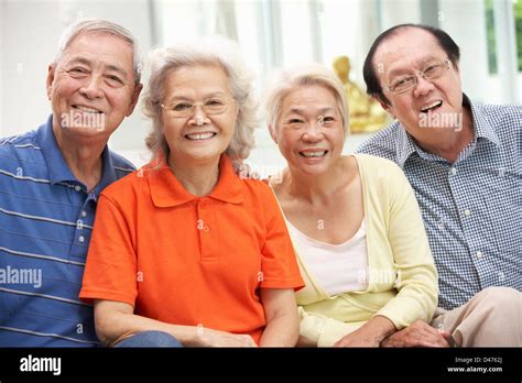 Group Of Senior Chinese Friends Relaxing On Sofa At Home Stock Photo