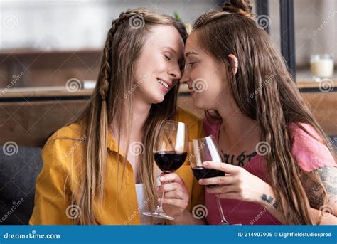 Two Lesbians Holding Wine Glasses While Sitting On Sofa In Living Room Stock Image Image Of