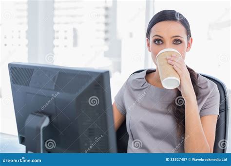 Attractive Businesswoman Drinking Coffee And Looking At Camera Stock