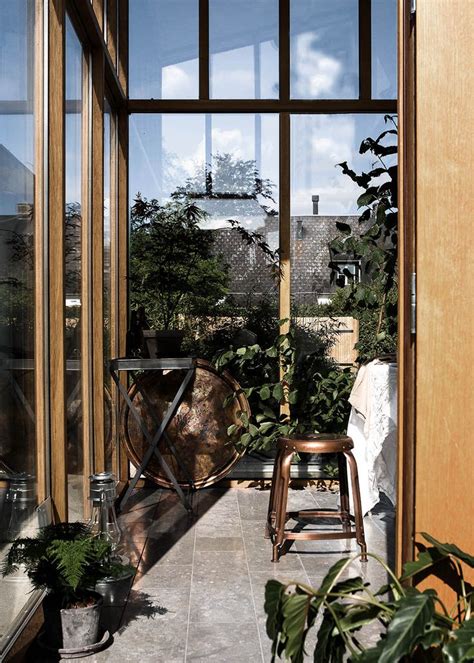 A Room With Some Chairs And Plants Inside Of It Looking Out Onto The Yard