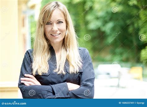 Smiling Mature Woman With Folded Arms Standing Outdoor Stock Image