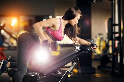 Young Fit Woman Doing Back Dumbbell Row Exercises On A Bench In The Gym