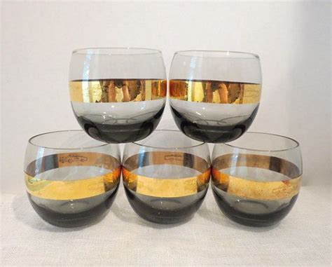 Four Wine Glasses With Gold And Black Rims Sitting On A White