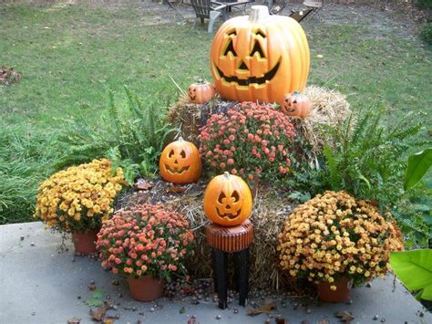 Simple Arrangement Of Potted Mums Lighted Pumpkins And Bails Of Hay