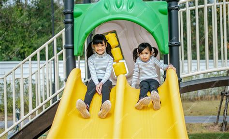 Premium Photo Two Girls Play Slides In The Playground Selective Focus