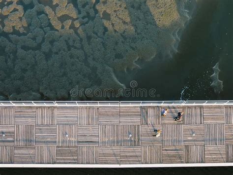 Top View Of The People Walking On A Wooden Boardwalk With A Calm Ocean