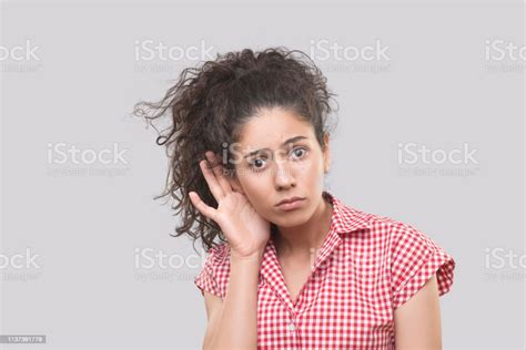 Portrait Of A Surprised Young Woman Eavesdropping On Gray Background