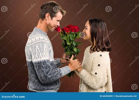 Composite Image Of Romantic Couple Holding Red Roses Stock Image