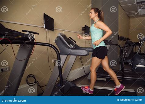 Attractive Young Woman Running On A Treadmill In Gym Stock Image
