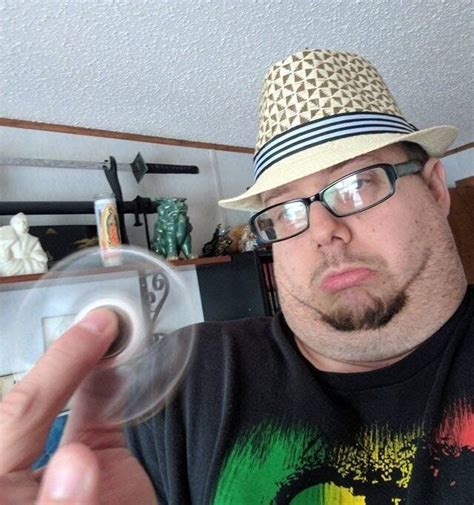 A Man Wearing Glasses And A Hat Is Holding A Plastic Object In Front Of