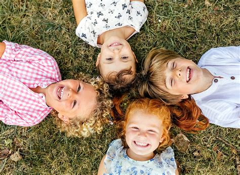 Four Smiling Children Lying On The Grass By Stocksy Contributor