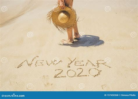 nude woman legs with tourist hat at the beach for new year eve 2020 concept image wrote on the