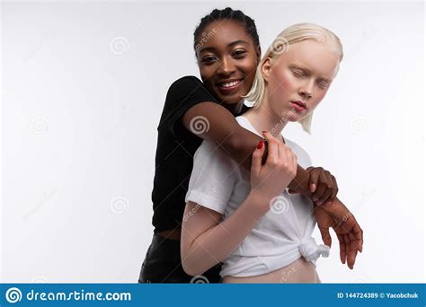 Smiling African American Woman Hugging Her White Skinned Friend Stock