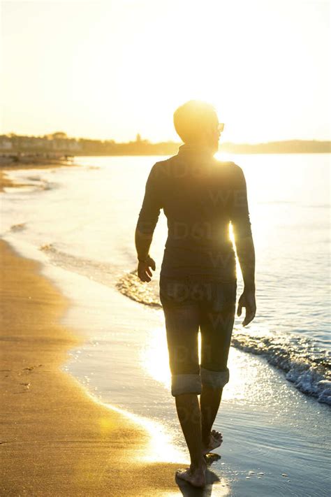 Silhouette Von Mann Zu Fuß Am Strand Bei Sonnenuntergang Lizenzfreies