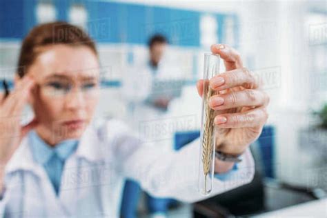 Selective Focus Of Female Scientist Looking At Flask In Hand With