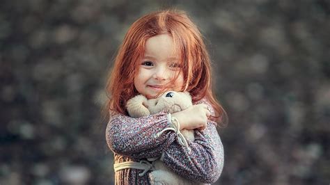 Smiley Cute Little Girl Is Holding Toy In Hand Wearing Flowers Printed