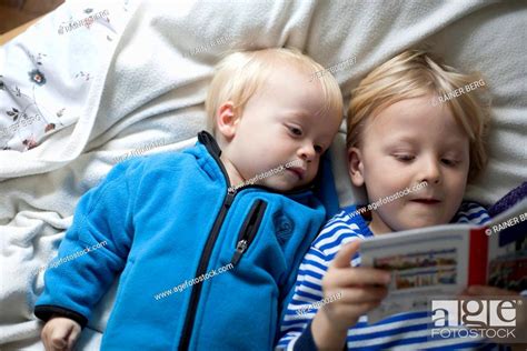 Two Little Boys Lying On Blanket Watching Book Stock Photo Picture