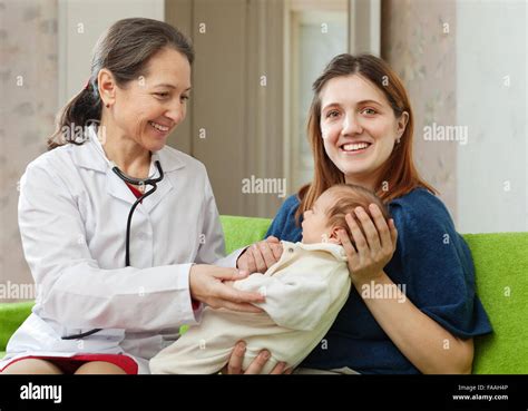 Friendly Mature Childrens Doctor Examining Newborn Baby Stock Photo