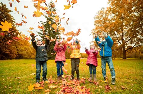 Happy Children Playing With Autumn Leaves In Park Stock Photo Image