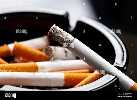 Burning Cigarette In A Black Ash Tray Stock Photo Alamy