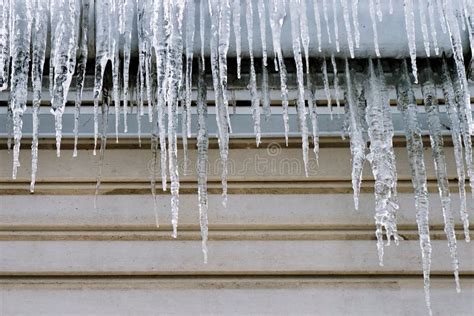 Long Icicles Hanging On The Roof Of A Wooden House In Winter Stock