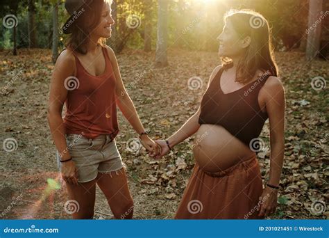 Closeup Of A Pregnant Lesbian Couple Doing A Photoshoot In A Park Stock