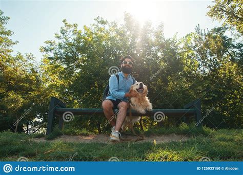 Interesting Man Sitting With His Dog On The Chair In The Park En Stock